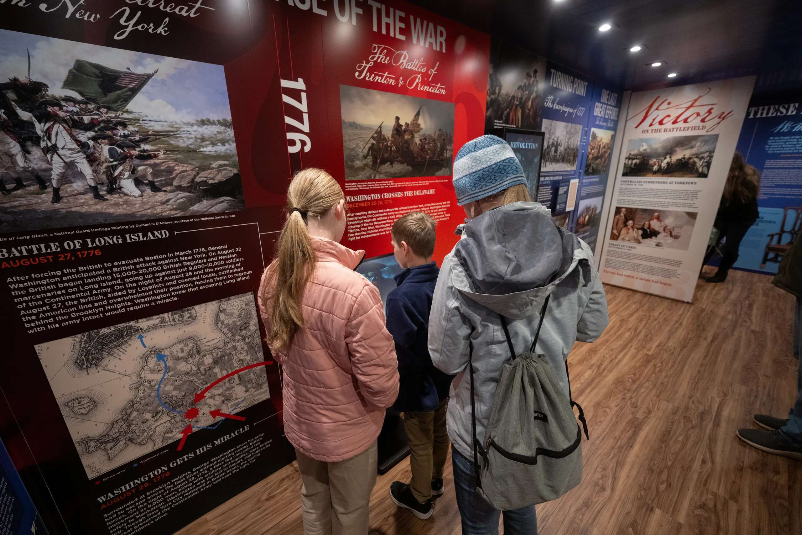 Visitors view an exhibit on key battles of the American Revolution inside the Freedom Truck. (Freedom 250 Mobile Museum)